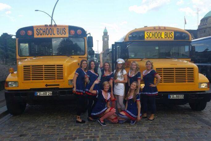 a group of people standing in front of a school bus