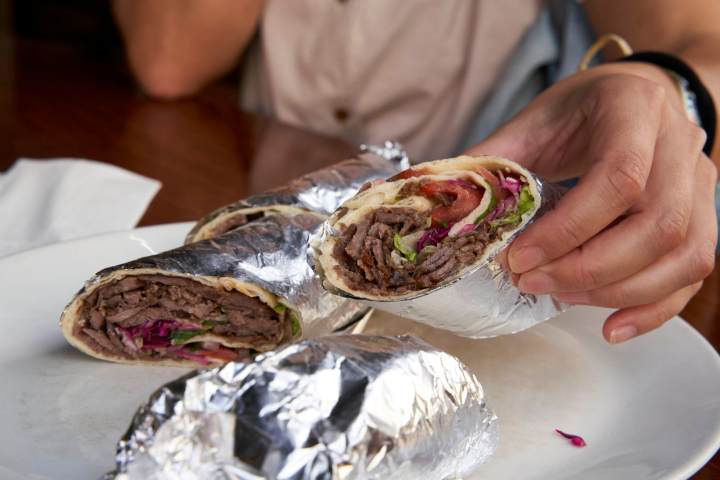 a person holding a plate of food on a table