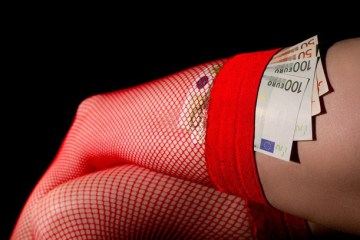 Eine Frau die rote Strapsstrümpfe trägt wo ein paar Geldscheine drinstecken