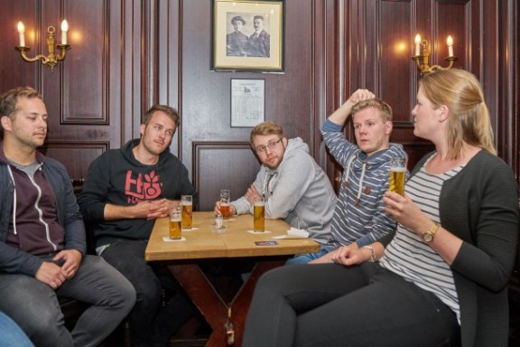 Fünf Leute sitzend an einem Tisch mit Biergläsern