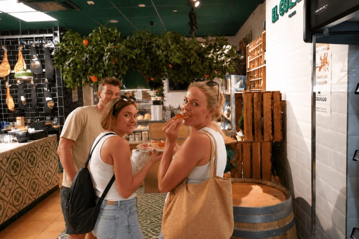 Three people eating in a deli with a decorative tree inside.