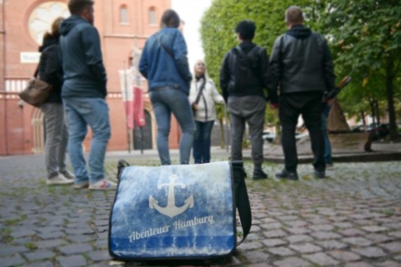 Eine Tasche mit dem Adventure World Tours-Logo vor einer Tourgruppe