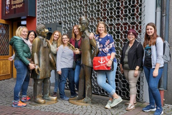 Eine Frauengruppe mit Tourguide neben zwei bronzenen Statuen