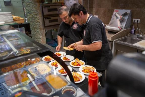 Zwei Männer die Essen hinter einer Theke zubereiten