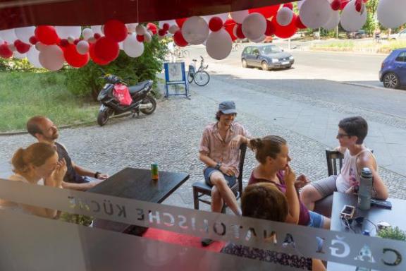 Einige Leute sitzen auf Stühlen vor einem Cafe