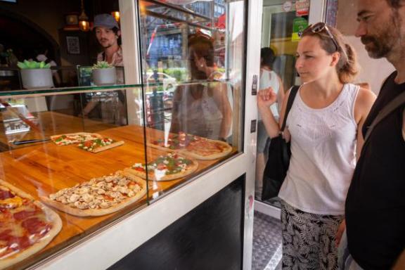 Eine Frau und ein Mann vor einem Pizza-Laden