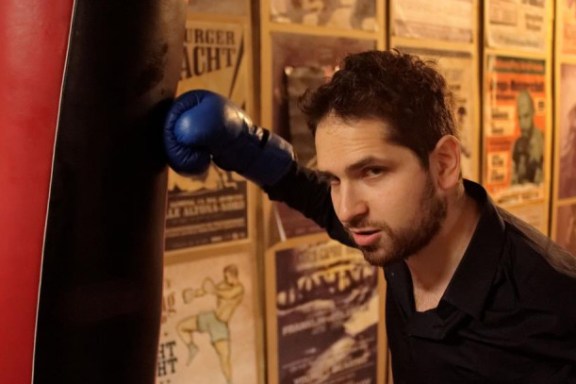 Ein Mann mit Boxhandschuh neben einem Boxsack