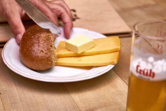 Brot und Käse auf einem Teller und ein Glas Bier daneben
