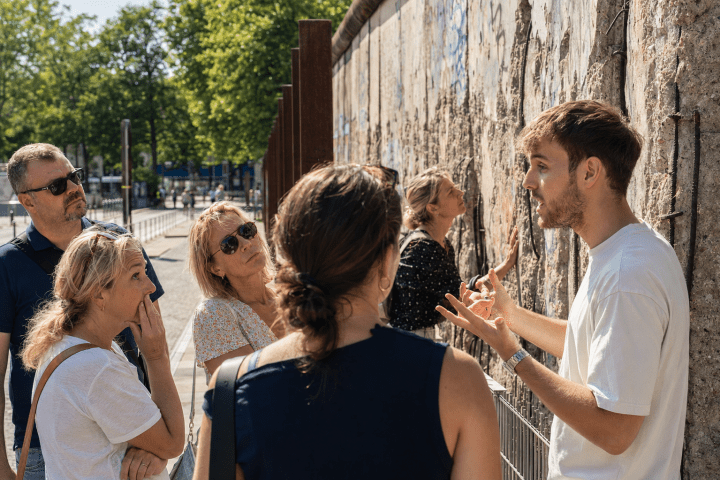 Tour guide explaining historical wall to a group of attentive listeners outside.