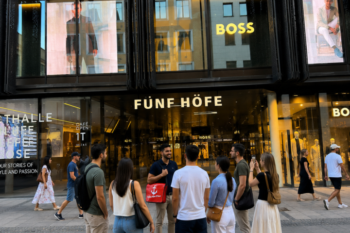 Group of people outside a modern shopping building with glass facade.