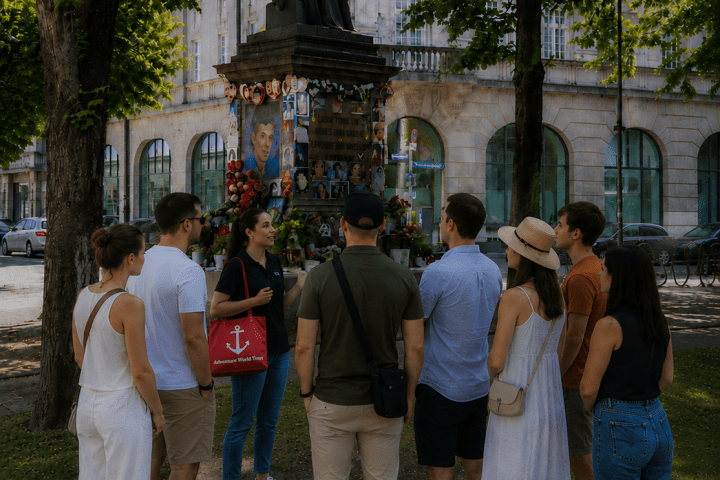 Group of people listening to a guide near a statue in a park.