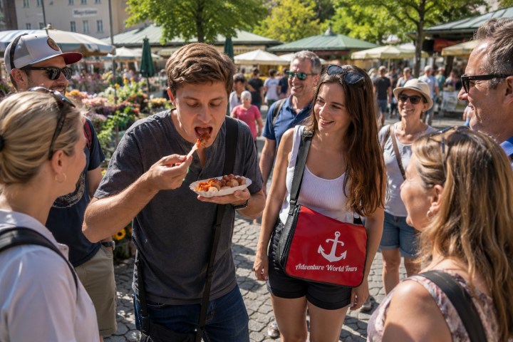 People enjoying food at an outdoor market on a sunny day.