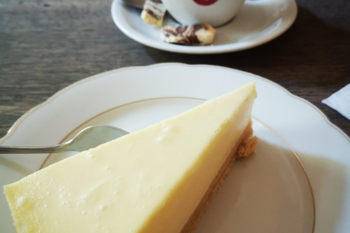 a piece of cake on a plate next to a cup of coffee