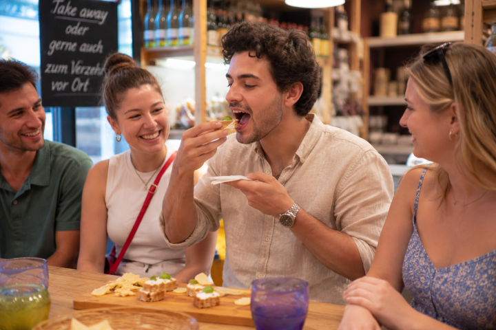 Friends enjoy snacks at a wooden table with drinks and laughing.