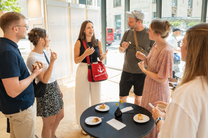 Group of people socializing indoors around tables with snacks.