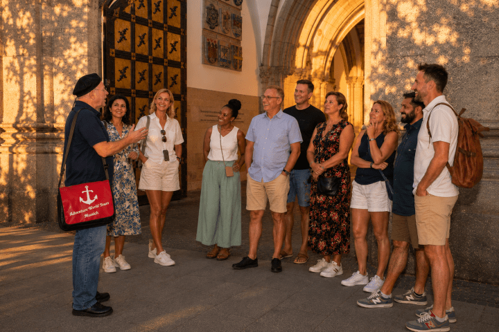 Group of people listening to a guide near an ornate building entrance.