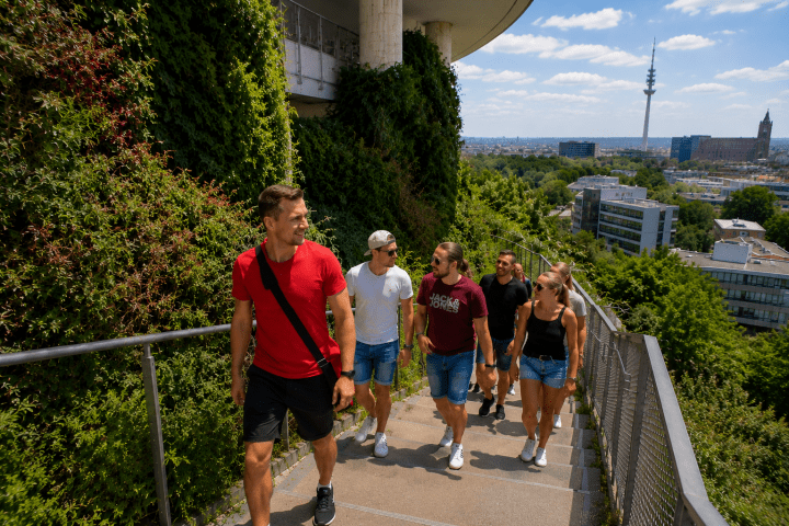 Group of six people walking up outdoor stairs surrounded by greenery.