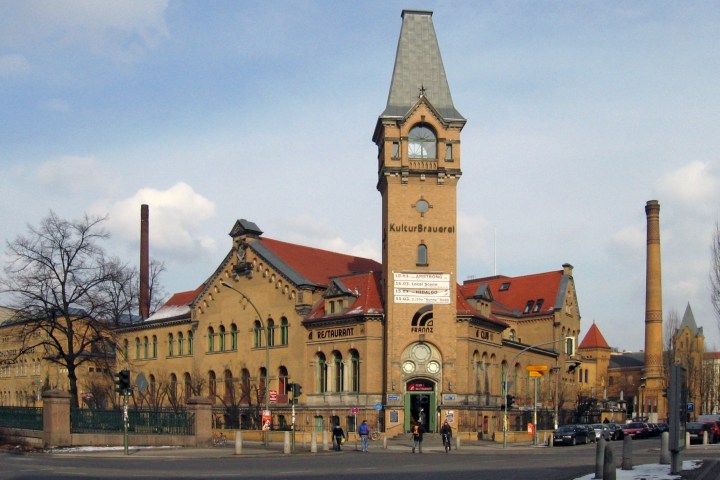 Historic brick building with clock tower, labeled KulturBrauerei, under a partly cloudy sky.