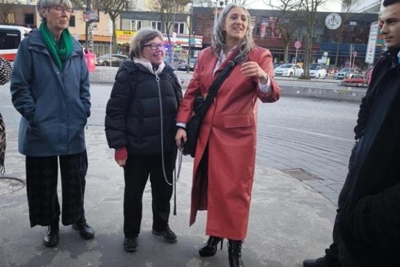 Group of people talking on a city street in winter clothing.