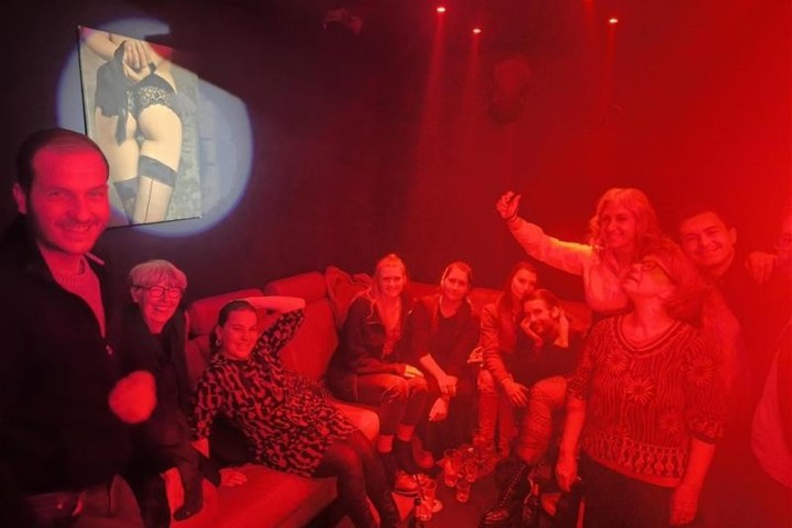 Group of people posing in a dimly lit room with red lighting.