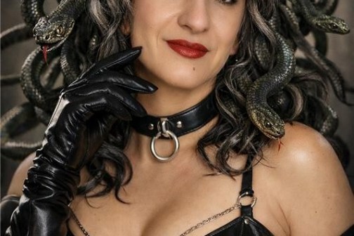 Person in leather outfit with snake-like hair and gloves, resembling a Medusa theme.