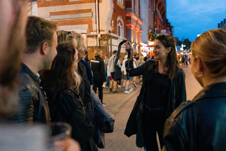 Group of people on a street, woman holding a snake.
