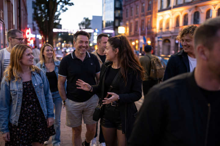 Group of people walking on a city street in the evening, smiling and talking.