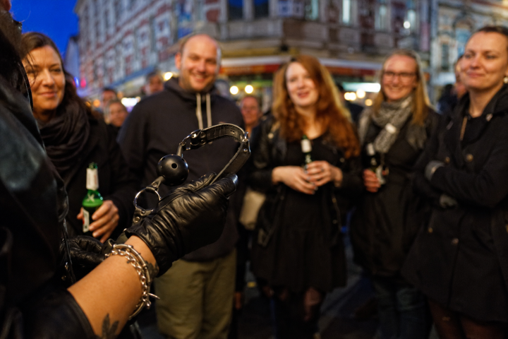 Person shows handcuffs to a smiling group on a street.