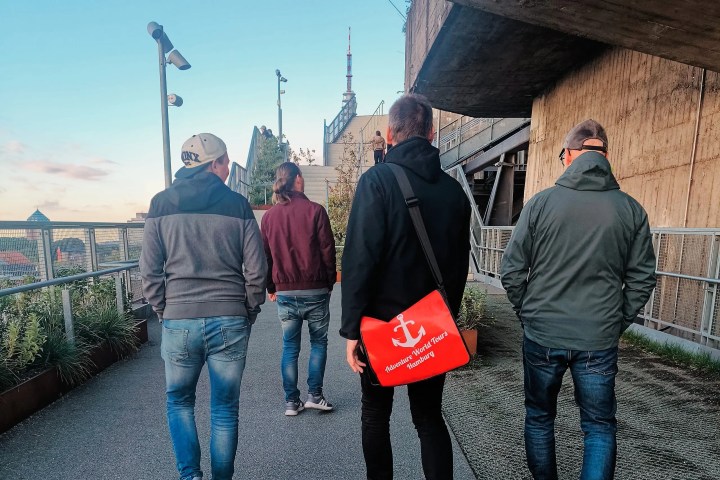 Four people walk along an outdoor path beside a building.