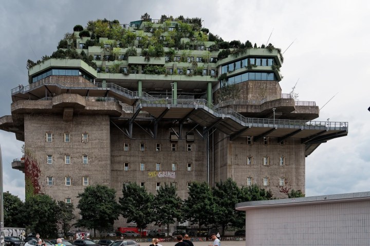Building with rooftop greenery and modern extensions on cloudy day.